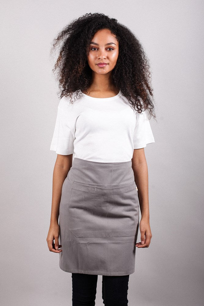 Female model in studio wearing Bliss Apron Half Length - Grey against grey background