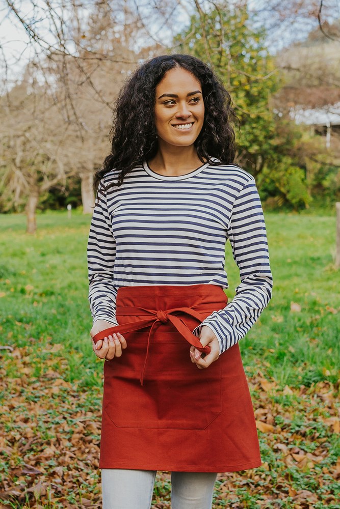 Female model outside in a park wearing Bliss Apron Half Length - Rust