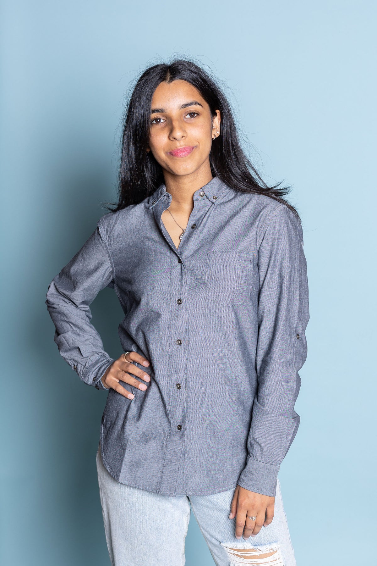 Female model with one hand on hips wearing greywacke Lucy Shirt against blue background